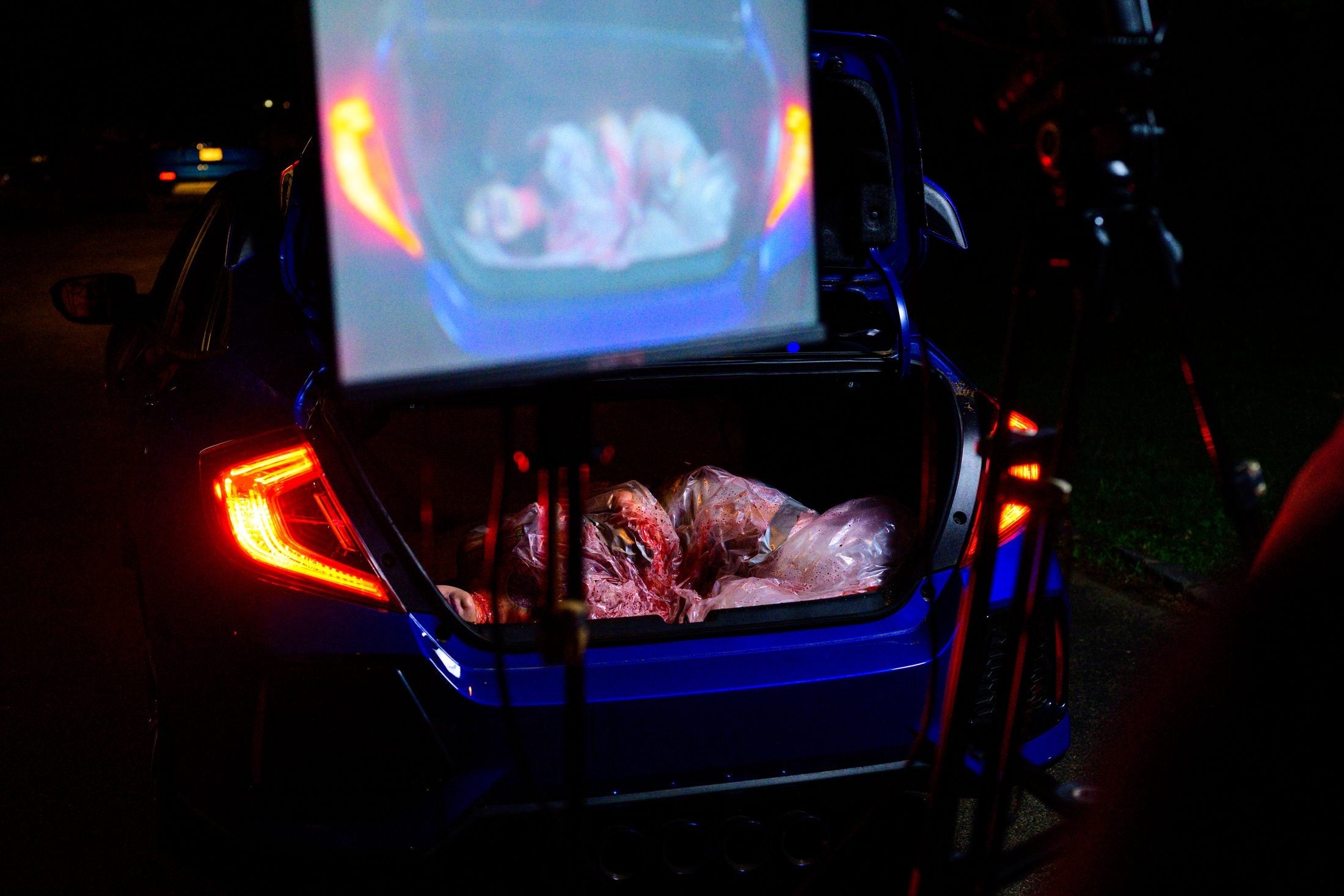 Open car trunk at night lit red by the tail lights during the Disunion shoot