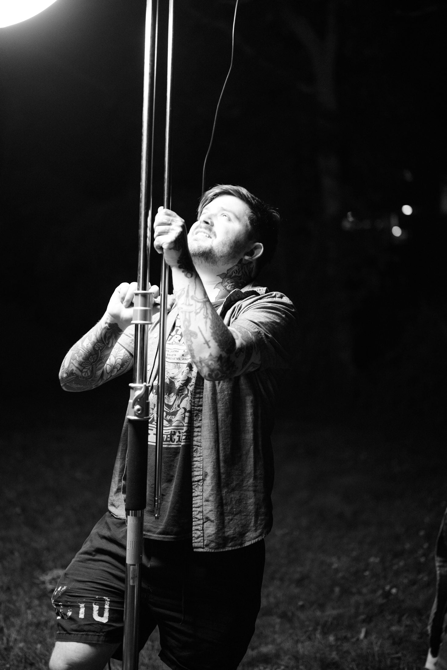 Boom operator holding the pole against the night sky