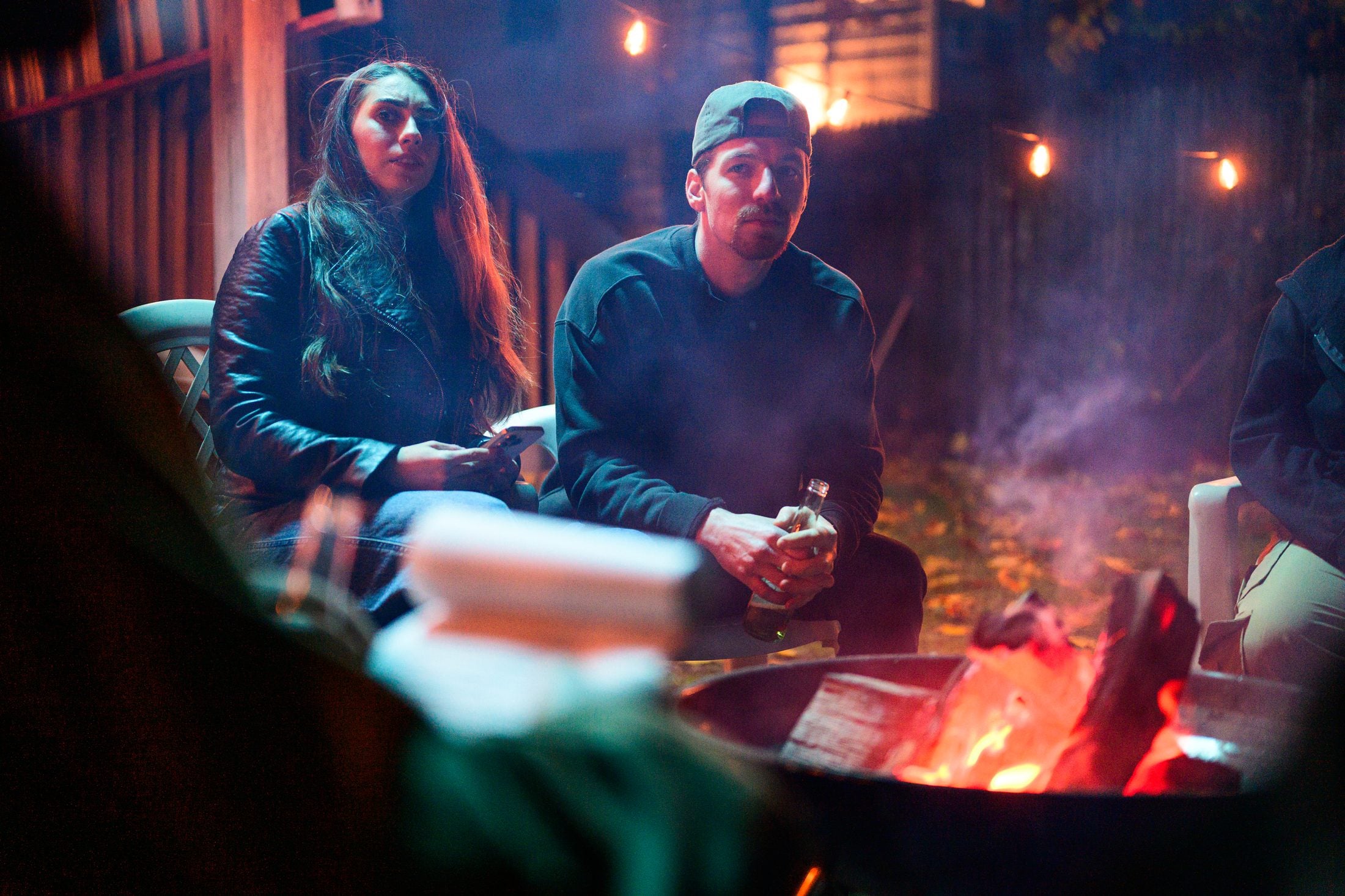 Two of the cast lit by the fire between takes