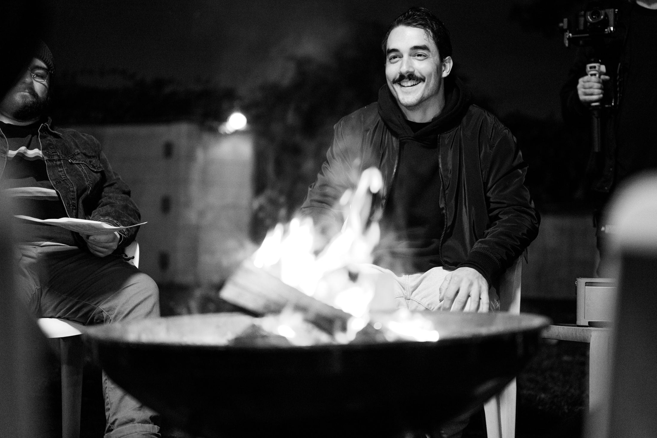 Crew member laughing beside the fire on set