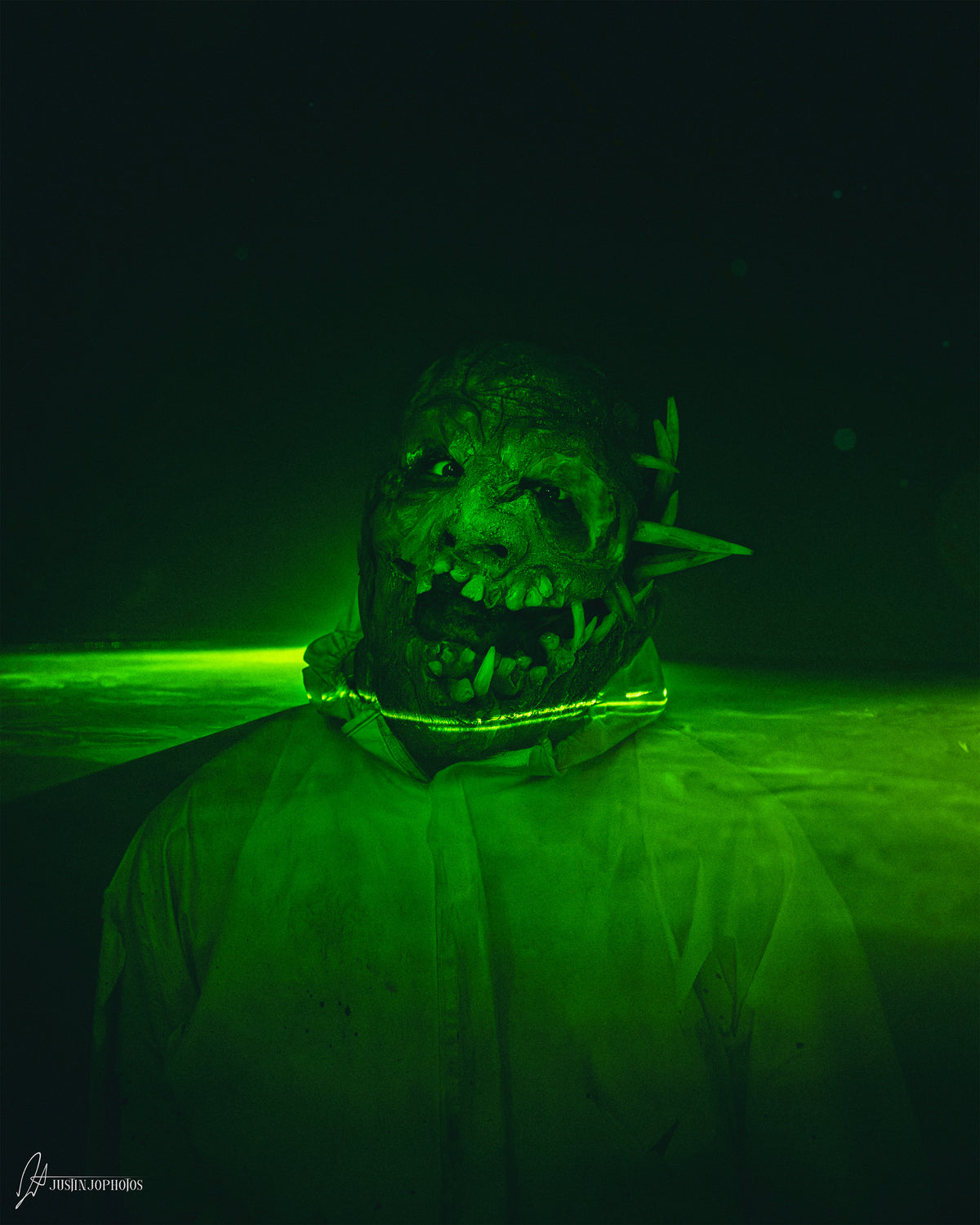 Masked figure holding a syringe in green light