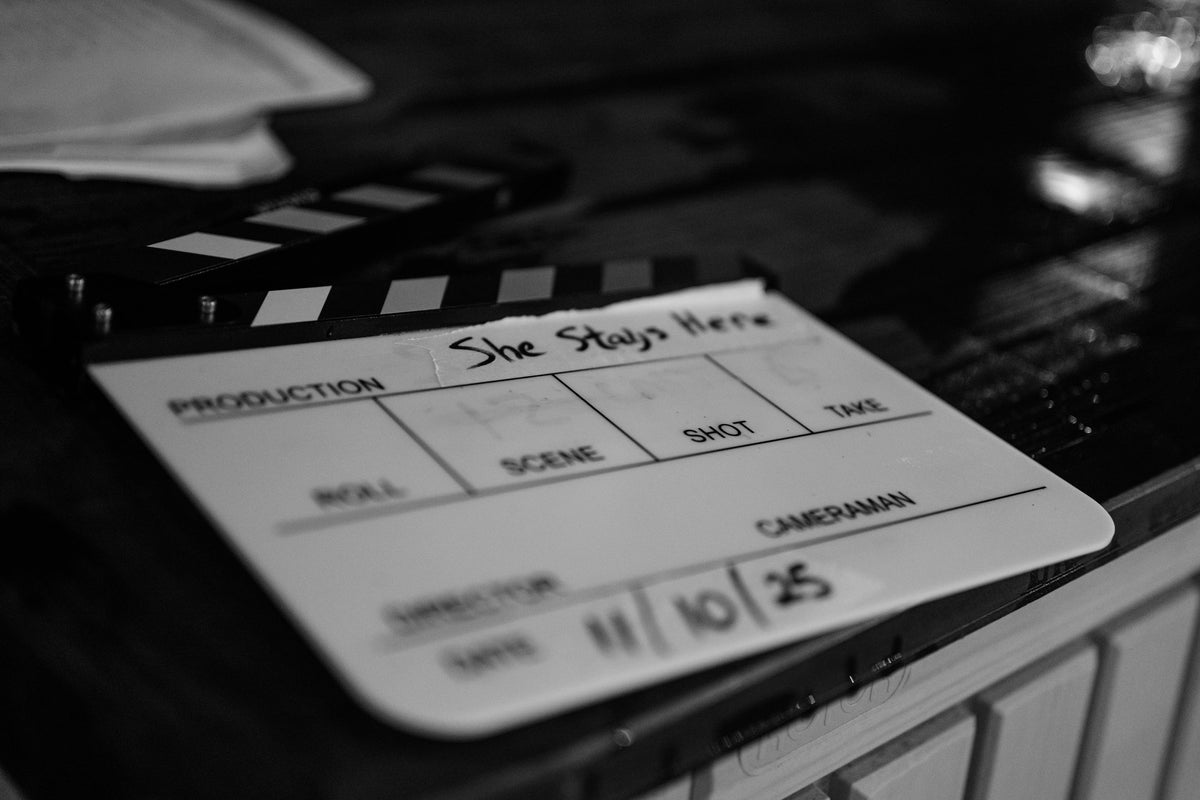 Production slate for She Stays Here resting on a railing